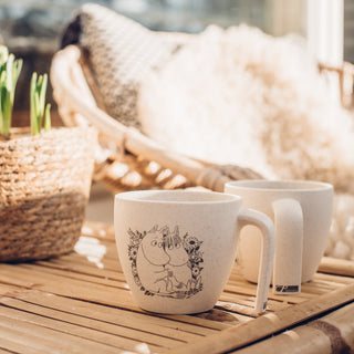 Muumipeikko ja Niiskuneiti kukkakedolla -kuvitettu Skandino PaussiCup parvekkeella auringonpaisteessa.